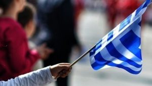 χέρι παιδιού κρατά ελληνική σημαία